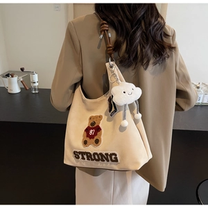 Dettaglio della borsa tote bianco sporco con toppa orsetto 3D e ricamo STRONG sul retro