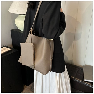 Side view of taupe pebbled leather tote bag with small matching pouch on model