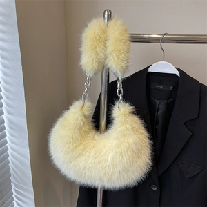 Détail du sac croissant en fausse fourrure jaune avec chaîne argentée sur un cintre