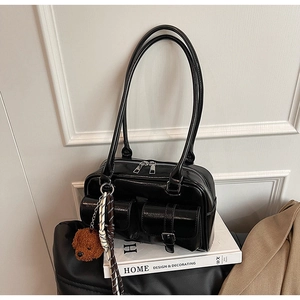 Détail du sac à bandoulière en cuir verni noir avec boucles et pendentif ours en peluche