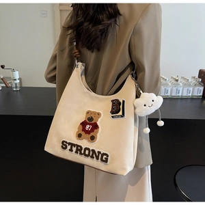 Dettaglio della borsa tote beige con ricamo a orsetto e ciondolo a nuvola soffice