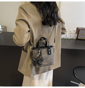 Detailed view of grey marbled crossbody bucket bag with black leather dog charm