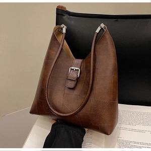 Detail of dark brown leather patchwork tote with silver buckle and vintage texture