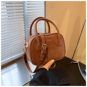 Détail d'un sac à bandoulière en daim marron avec inscription dorée 'FASHION & BAGS'