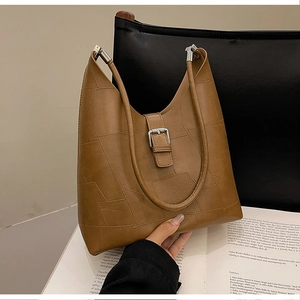 Close-up of brown patchwork texture and silver metal buckle on retro shoulder bag