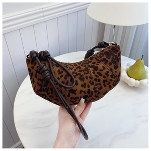Detailed close-up of leopard print croissant bag with decorative knotted leather strap