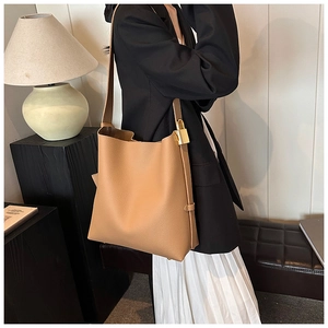Detail shot of camel leather tote bag featuring lychee texture and golden padlock charm