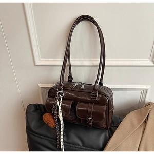 Détail d'un sac à bandoulière vintage marron foncé avec poches et pendentif en peluche