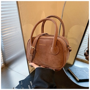 Détail du sac à main en daim marron foncé avec lettrage doré et bandoulière réglable