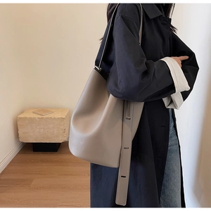 Detail of grey pebbled leather bucket bag featuring adjustable wide shoulder strap
