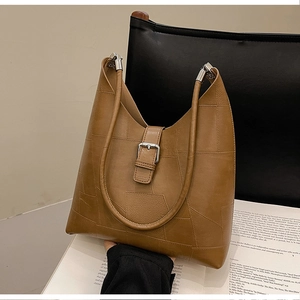 Detail of brown geometric patchwork leather shoulder bag with silver buckle and matte finish
