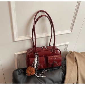 Détail du sac à bandoulière en cuir brillant bordeaux avec poches et charm ours