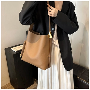 Detail of brown pebbled leather tote bag with wide strap and gold buckle hardware
