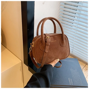 Détails d'un sac bandoulière en daim marron café avec lettrage doré et ferrures