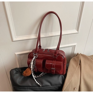 Détail du sac à bandoulière rouge vin brillant avec deux poches à boucle et zip métallique
