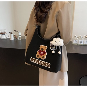 Dettaglio della borsa Hobo in tela nera con ricamo a forma di orso e ciondolo a nuvola