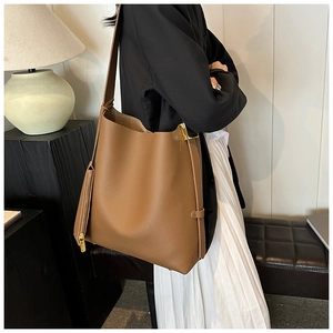 Detail view of brown pebbled leather tote bag side with golden hardware and wide strap