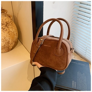 Gros plan d'un sac à main marron mat en daim avec lettrage doré et bandoulière réglable