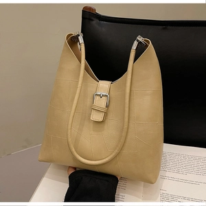 Detail of beige leather shoulder bag with geometric stitching and silver metal buckle
