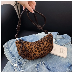 Close-up of leopard print crescent bag featuring a stylish leather knot and metal zipper