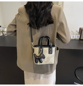 Detail of a mini canvas bucket bag with marble pattern worn with a khaki blazer