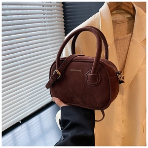 Détail du sac à main en daim marron foncé avec ferrures dorées et logo gaufré