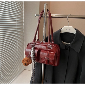 Détail du sac à bandoulière en cuir brillant bordeaux avec poches et charm ours