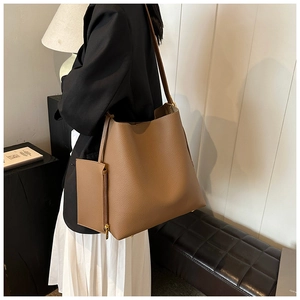 Detail of caramel leather tote bag showing side zipper pocket and pebble grain texture