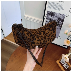 Detailed view of leopard print crescent bag on wooden table with elegant decor
