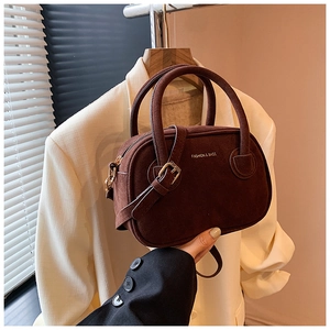 Détail du sac Boston en daim marron avec logo FASHION & BAGS doré estampillé