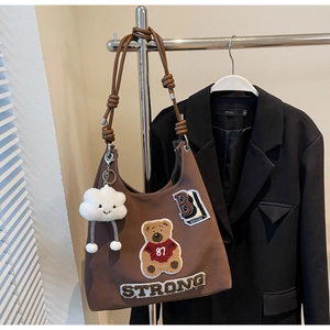 Dettaglio borsa shopper marrone con ricamo orso colorato e ciondolo a nuvola bianca