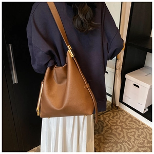 Detail of brown pebble leather tote bag with gold zipper and metallic hardware