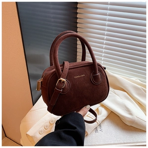 Détail du sac à main en cuir mat marron foncé avec fermeture éclair dorée et bandoulière