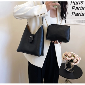 Detail of black vintage underarm bag with silver hardware on white suit model