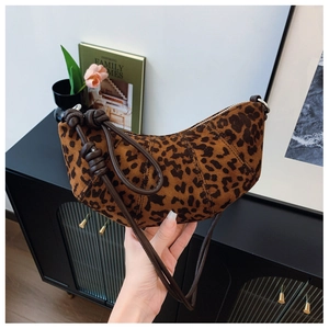 Detail of leopard print crescent bag with leather knotted strap in a modern setting