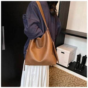 Brown leather tote bag featuring a spacious interior and soft pebble grain texture