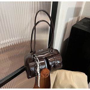 Détail du sac sous le bras en cuir brillant marron foncé avec poches et breloque ours
