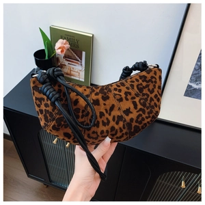 Detail of leopard print crescent bag featuring a woven knot handle in a modern home setting