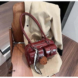 Détail du sac oreiller en similicuir rouge foncé avec foulard en soie et breloque ours