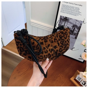 Detailed view of leopard print crescent bag with black knotted rope strap on wooden table