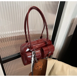 Détail du sac à bandoulière en cuir verni bordeaux avec charm ours en peluche et poches