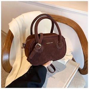 Détail d'un mini sac Boston en daim marron avec garnitures dorées et bandoulière