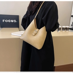 Detail of beige shoulder bag featuring paneled texture and metallic buckle strap accents