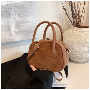 Détails d'un sac à main en daim marron foncé avec accents dorés et texte de marque
