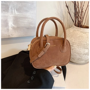 Vue détaillée du sac à bandoulière en daim marron avec fermeture éclair dorée et deux poignées