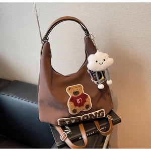 Dettaglio della borsa tote marrone vintage con ricamo a orso e ciondolo a nuvola