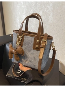 Blue denim bucket bag with brown leather trim and cute puppy charm hanging on side
