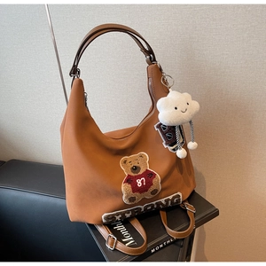 Dettaglio della borsa tote caramello con ricamo orsetto e ciondolo nuvola in peluche bianco