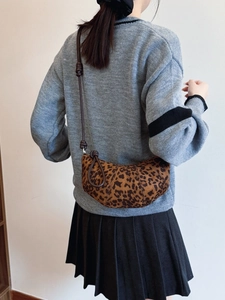 Leopard print croissant crossbody bag for women with leather strap over grey cardigan
