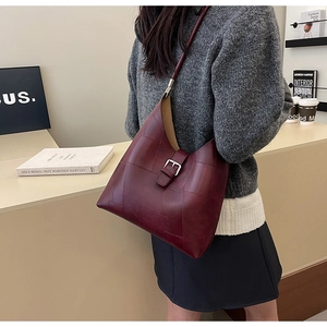 Close-up of deep red leather hobo bag featuring geometric patchwork and metal buckle detail